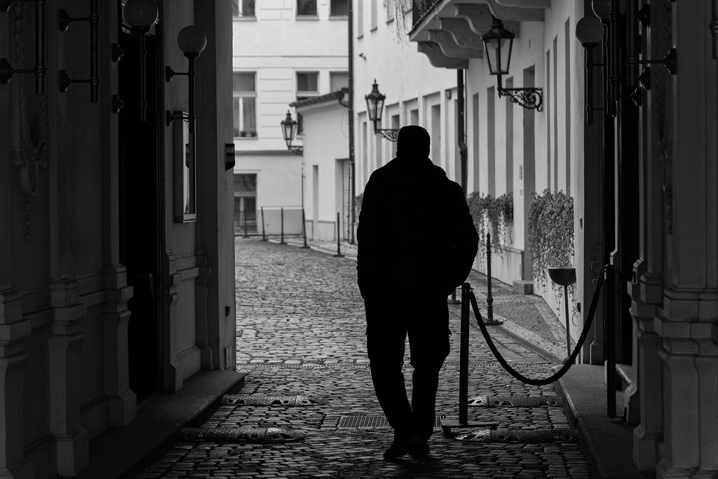 minimalist photo of silhouette of lonely man on the prague street